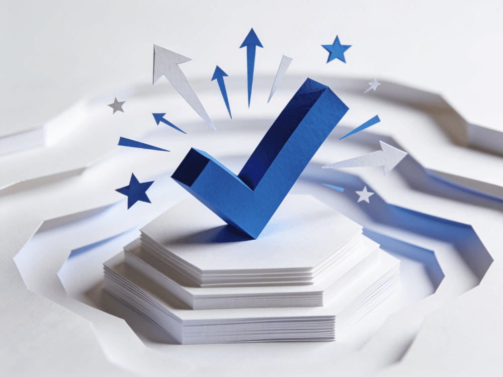 Papercraft checkmark standing on a podium amid celebratory arrows and stars
