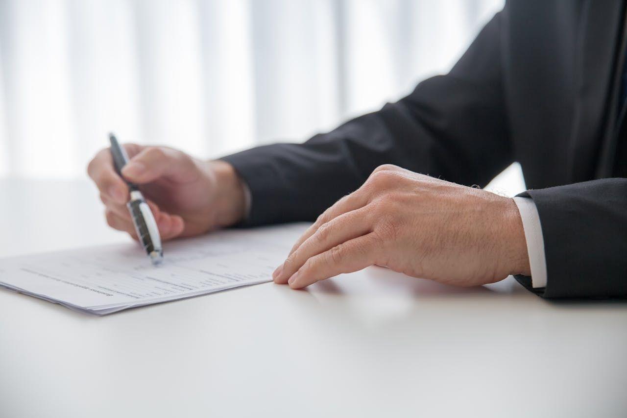 Hands signing a legal document at a desk, representing SEC-aligned regulatory compliance and investor protection in U.S. real estate investments
