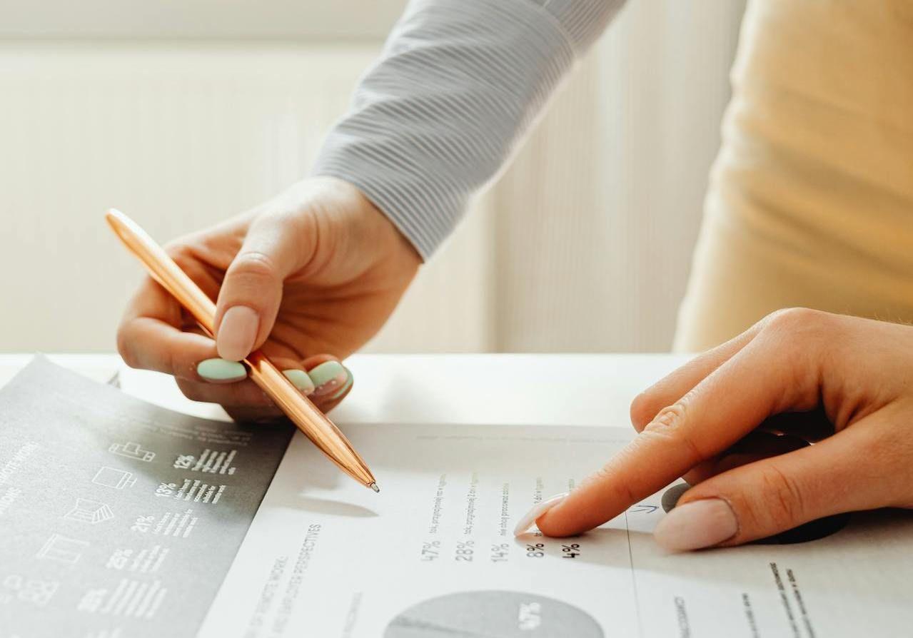 Hands reviewing a financial report and pointing to performance data, representing transparent and audit-ready investment reporting